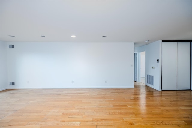 unfurnished room featuring light wood-style flooring, visible vents, and baseboards