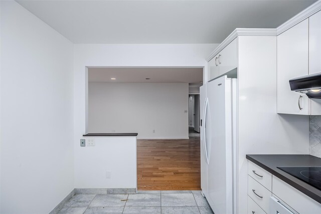 kitchen with white cabinetry, black electric cooktop, and freestanding refrigerator