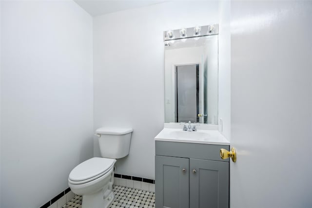 half bathroom featuring baseboards, vanity, toilet, and tile patterned floors