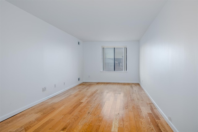 unfurnished room featuring light wood-type flooring, visible vents, and baseboards