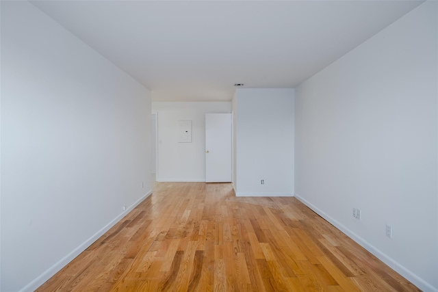 spare room featuring baseboards and light wood finished floors