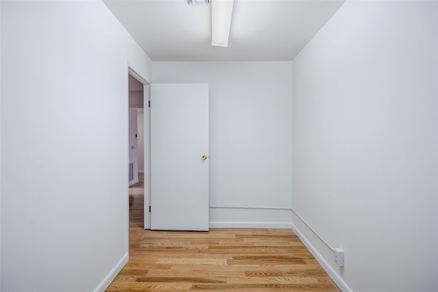 empty room with light wood finished floors, visible vents, and baseboards