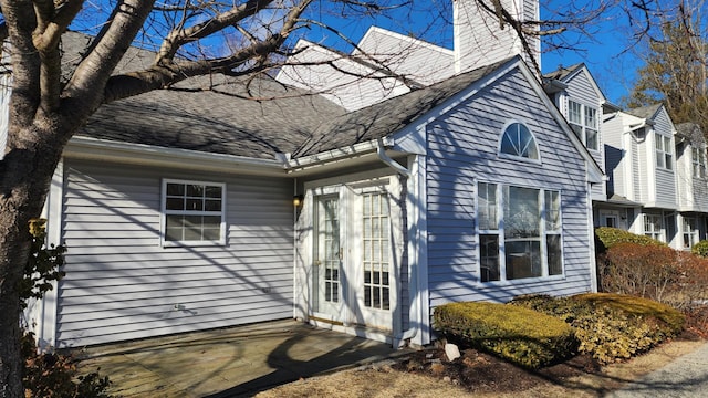 exterior space featuring a patio area, roof with shingles, and a chimney