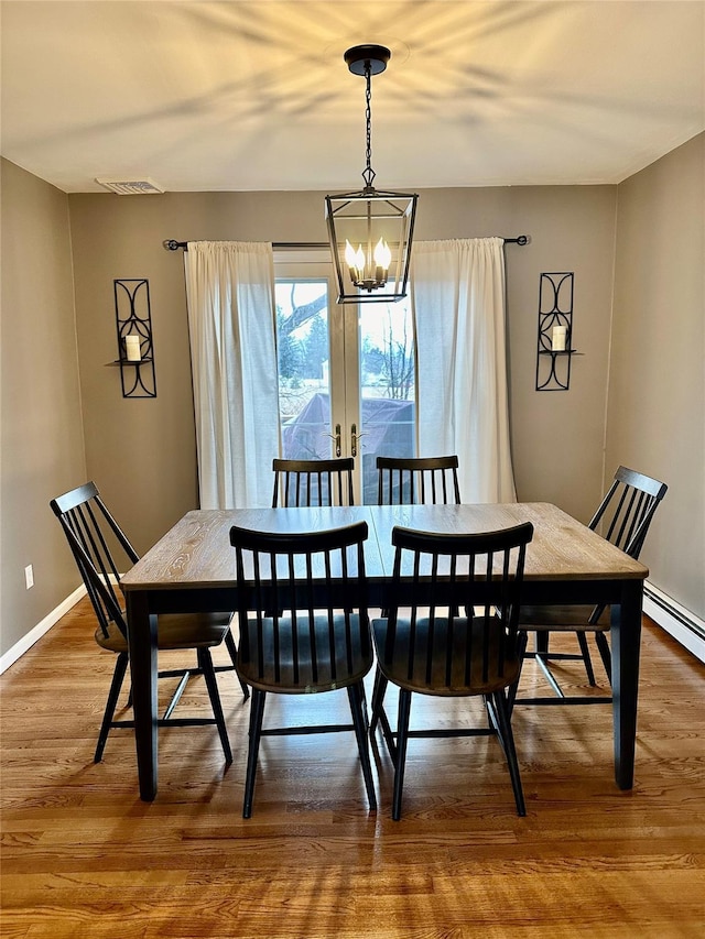 dining room with a chandelier, wood finished floors, visible vents, baseboards, and french doors