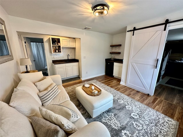 living area featuring dark wood-style floors, visible vents, baseboards, and a barn door