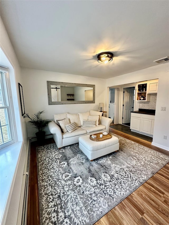 living room featuring dark wood-style floors, visible vents, and baseboards