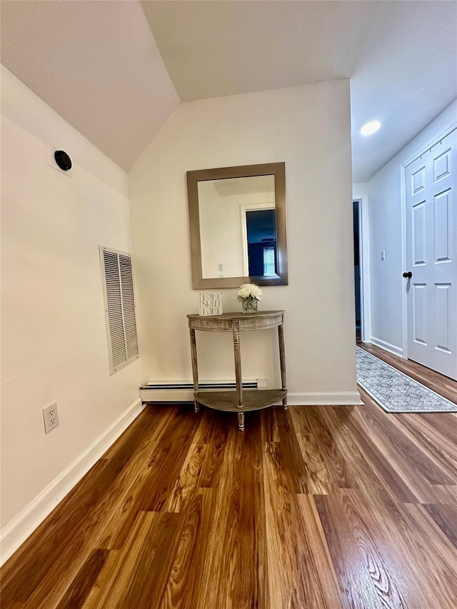 interior space featuring baseboards, visible vents, baseboard heating, and wood finished floors