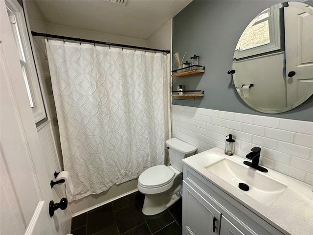 full bathroom featuring toilet, a wainscoted wall, vanity, tile walls, and tile patterned floors