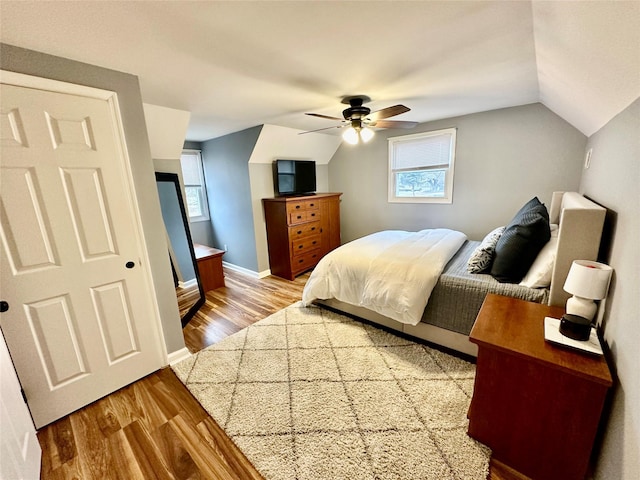 bedroom with vaulted ceiling, ceiling fan, wood finished floors, and baseboards