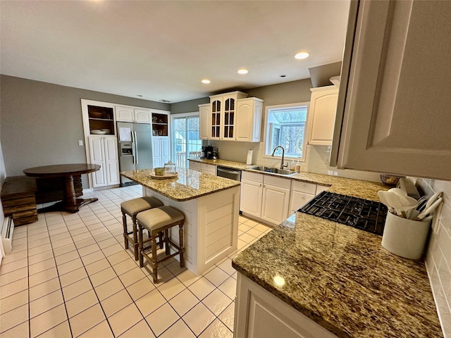 kitchen featuring a breakfast bar, a center island, decorative backsplash, appliances with stainless steel finishes, and a sink