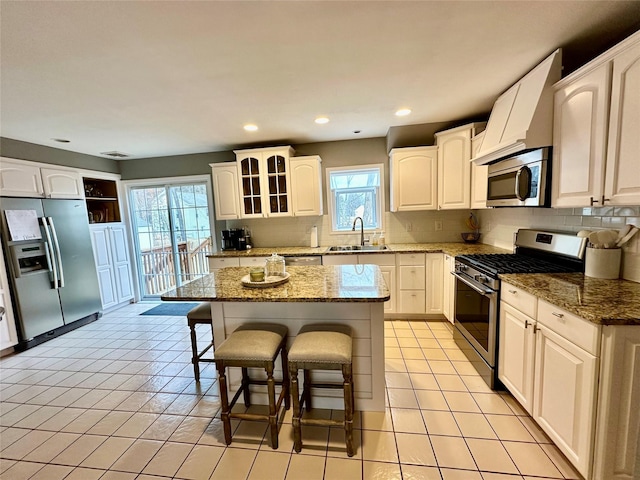 kitchen with a kitchen bar, appliances with stainless steel finishes, a sink, and light tile patterned flooring