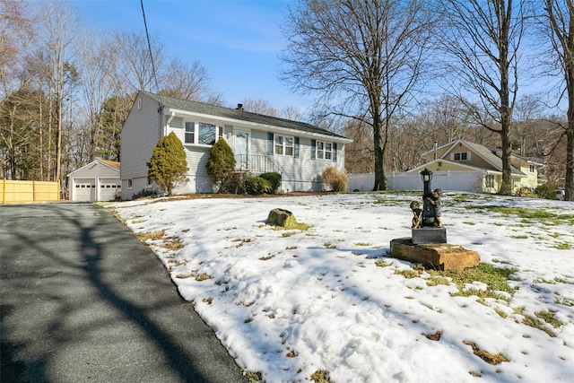 view of front of property with a detached garage, fence, and an outbuilding