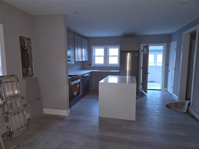 kitchen featuring backsplash, a center island, baseboards, light countertops, and stainless steel appliances