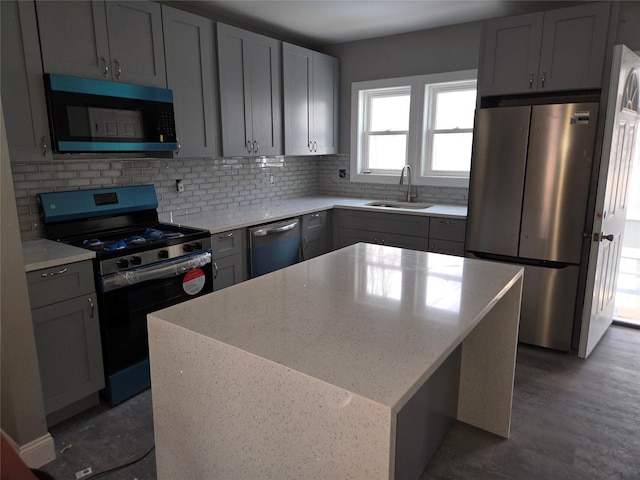 kitchen with light stone counters, a kitchen island, a sink, appliances with stainless steel finishes, and backsplash