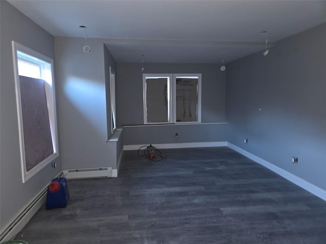 unfurnished room with baseboard heating, baseboards, and wood finished floors