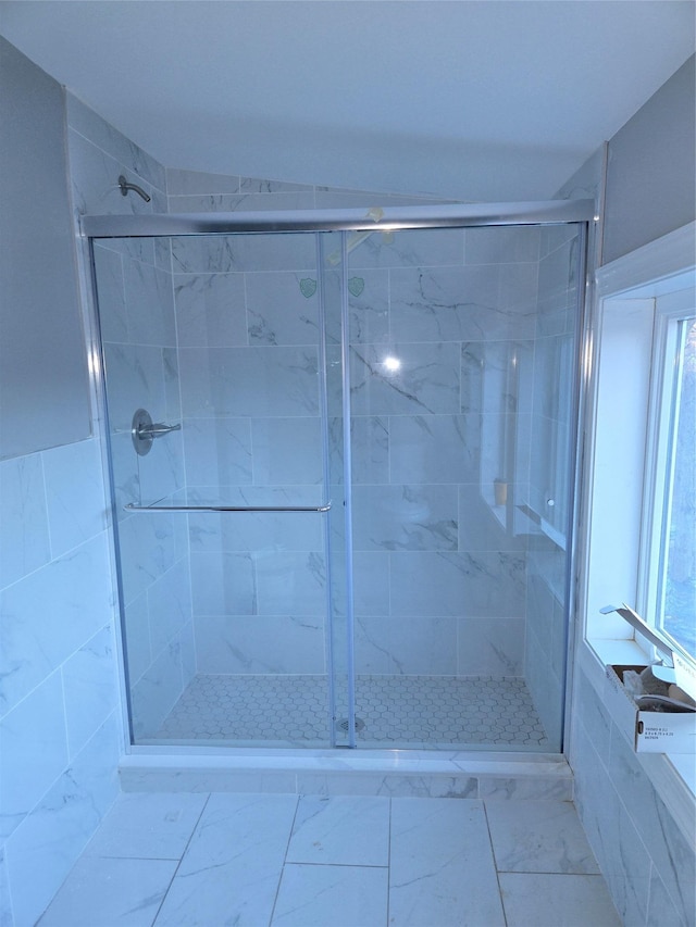 bathroom with marble finish floor and a stall shower