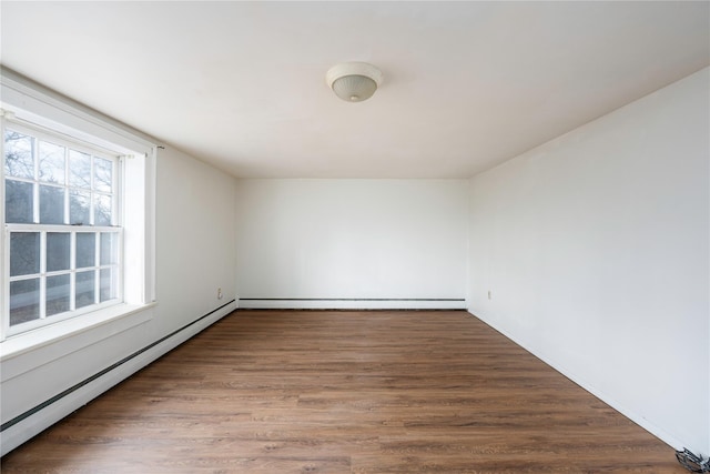 unfurnished room with a baseboard heating unit and wood finished floors