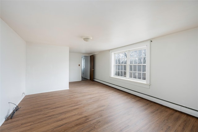 spare room with a baseboard radiator, wood finished floors, and baseboards