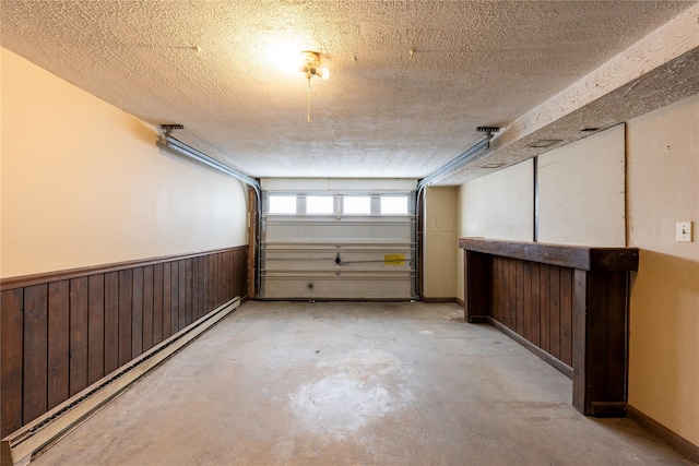 garage featuring a baseboard radiator, wooden walls, and wainscoting