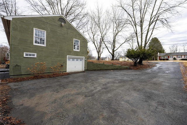 view of property exterior featuring driveway and an attached garage