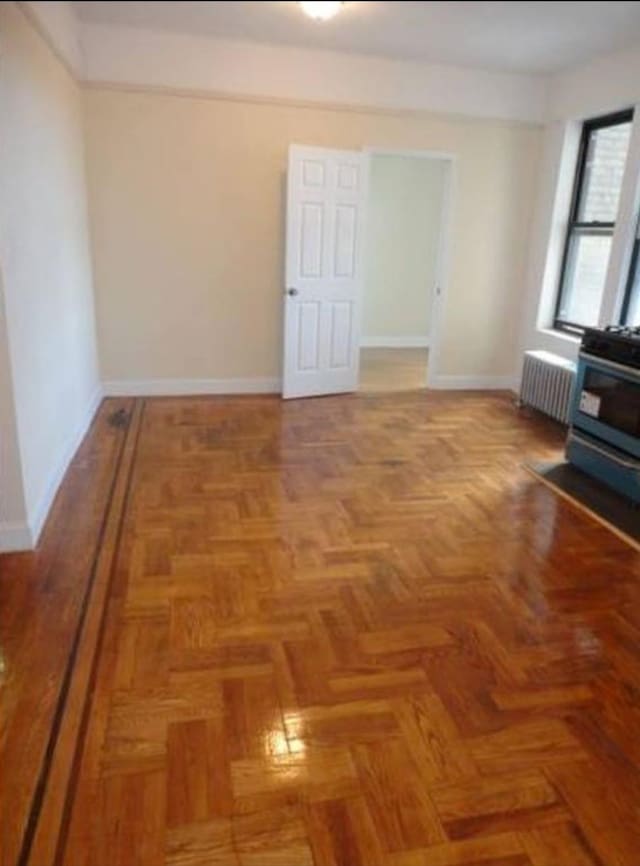 spare room with radiator heating unit and baseboards