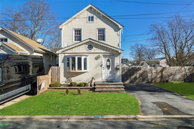 view of front of property with driveway, a front lawn, and fence