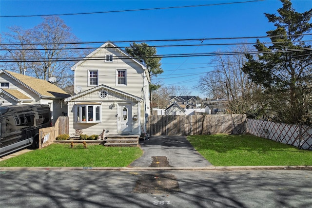 view of front of property featuring driveway, a fenced front yard, and a front lawn