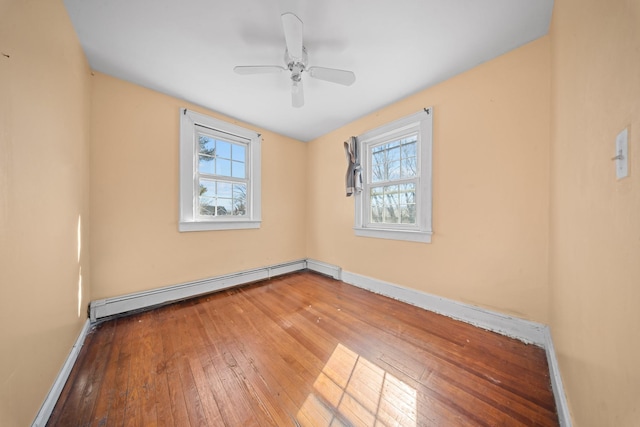 spare room with a healthy amount of sunlight, hardwood / wood-style flooring, baseboards, and a baseboard heating unit