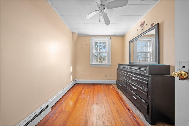 bedroom featuring light wood-style floors, a baseboard radiator, multiple windows, and baseboards