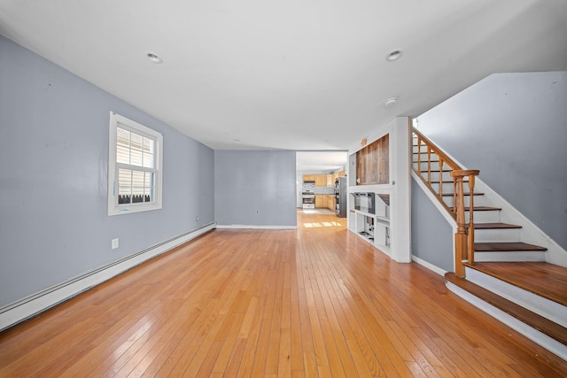 unfurnished living room featuring stairs, baseboard heating, light wood-style flooring, and baseboards