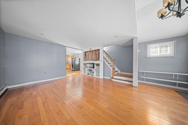 unfurnished living room featuring wood-type flooring, stairs, and baseboards