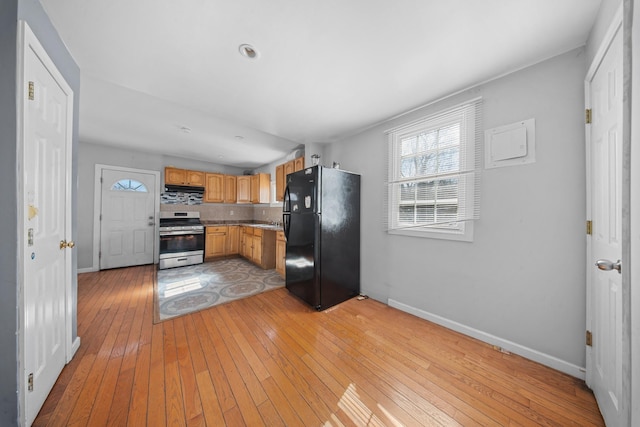 kitchen featuring tasteful backsplash, light wood-style floors, freestanding refrigerator, stainless steel range oven, and baseboards