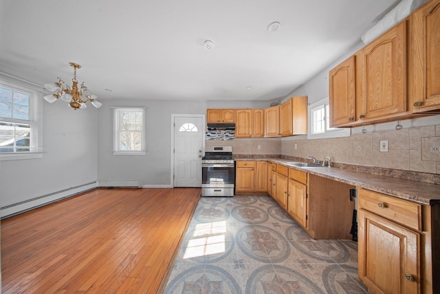 kitchen with a sink, ventilation hood, backsplash, light wood finished floors, and stainless steel range with gas stovetop