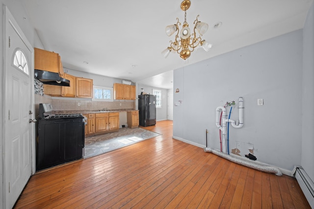 kitchen with light wood-style flooring, freestanding refrigerator, gas range oven, under cabinet range hood, and a baseboard heating unit