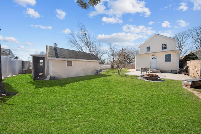 exterior space featuring a fire pit, a patio, a fenced backyard, a yard, and an outdoor structure