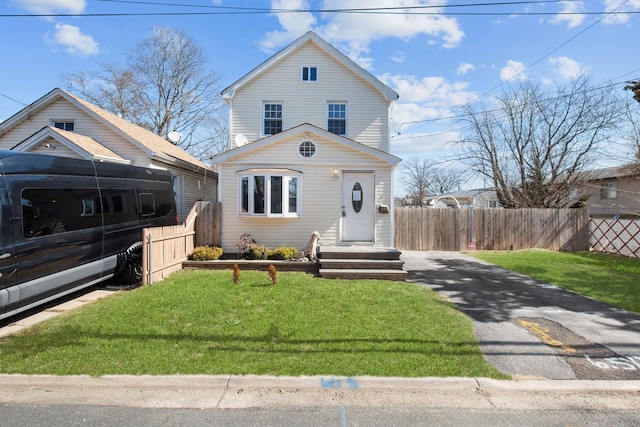 view of front of home with a front lawn, fence, and aphalt driveway