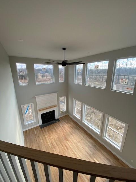 unfurnished living room featuring wood finished floors, plenty of natural light, and a fireplace with flush hearth