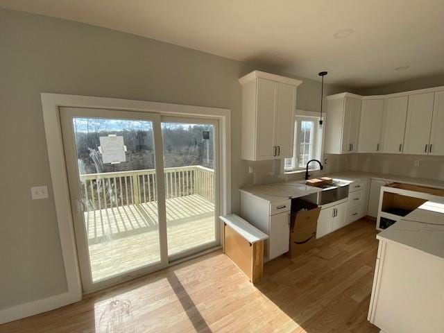 kitchen with light wood-style floors, white cabinets, a sink, and light countertops