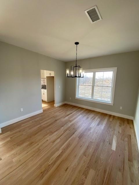 unfurnished dining area with baseboards, light wood-style flooring, visible vents, and a notable chandelier