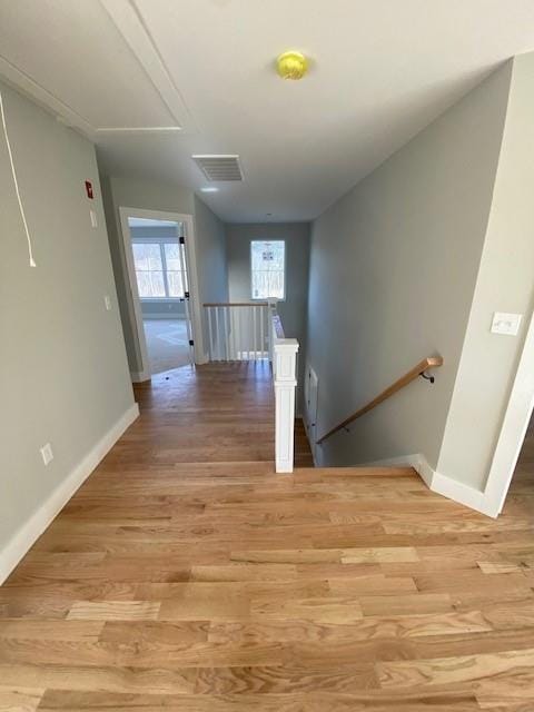 corridor featuring light wood-style flooring, baseboards, and an upstairs landing