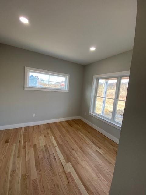 spare room featuring light wood-style floors, plenty of natural light, and baseboards