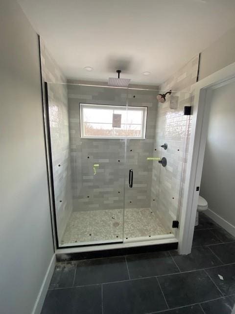 full bathroom featuring toilet, a stall shower, baseboards, and tile patterned floors