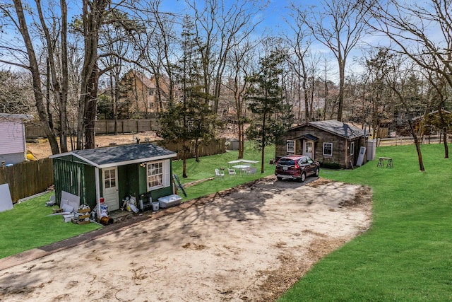 view of yard with an outbuilding, driveway, and fence