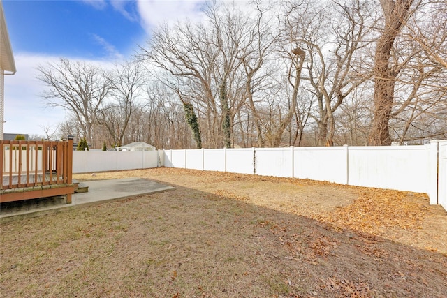 view of yard with a deck, a patio, and a fenced backyard