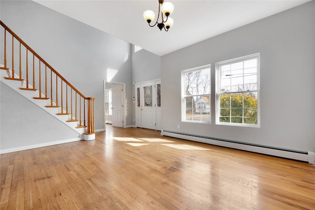 foyer entrance featuring stairway, a notable chandelier, a baseboard heating unit, and wood finished floors