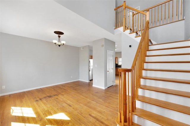 staircase with baseboards, a chandelier, and wood finished floors