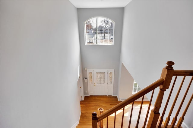 stairway featuring baseboard heating, wood finished floors, and baseboards