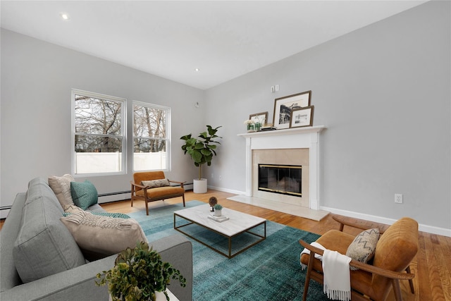 living area featuring a high end fireplace, baseboards, baseboard heating, and wood finished floors