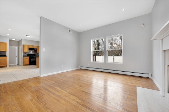 unfurnished living room with light wood finished floors, baseboard heating, visible vents, and baseboards