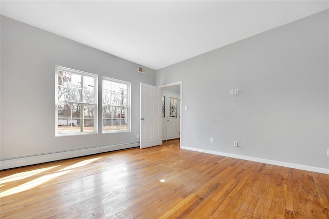 spare room featuring light wood-style floors, baseboards, visible vents, and baseboard heating